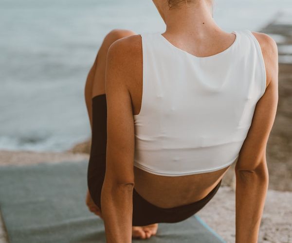 Person stretching gently on a yoga mat outdoors at sunrise.