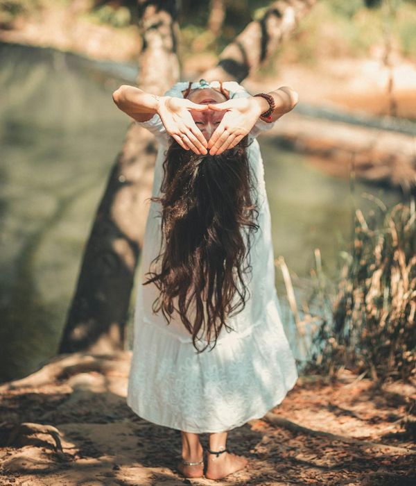 Woman in a serene yoga pose in a bright, calm environment.